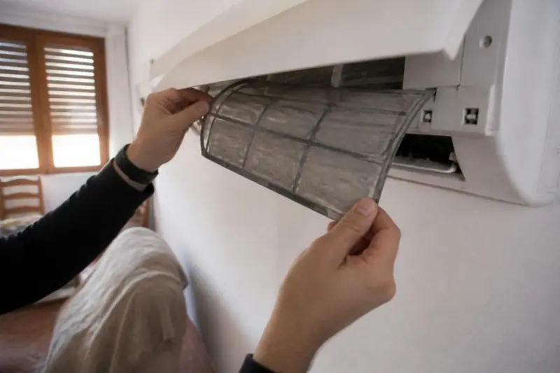 Técnico sacando el filtro sucio de un aire acondicionado que no calienta en una casa de Castellón